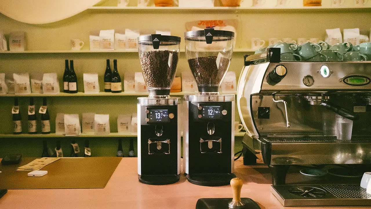 White Mahlkönig E65T GbS and E80T GbS grinders by the espresso machine in a café